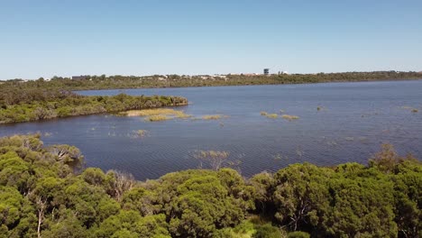 Imágenes-Aéreas-De-Un-Lago-Profundo-Con-Follaje-Verde-Y-Fondo-De-Cielo-Azul