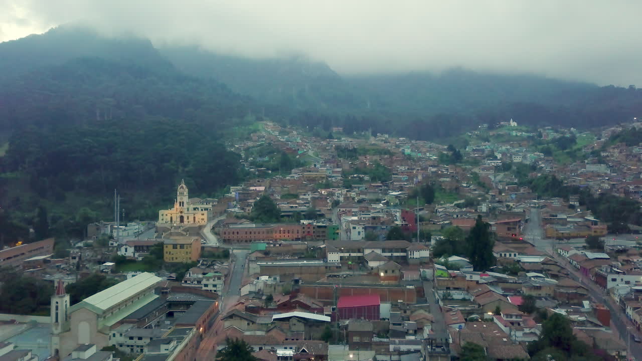 Wide shot flying towards mountain range and the empty streets of a traditional neighborhood in Bogota on a gray and cloudy day in pandemic