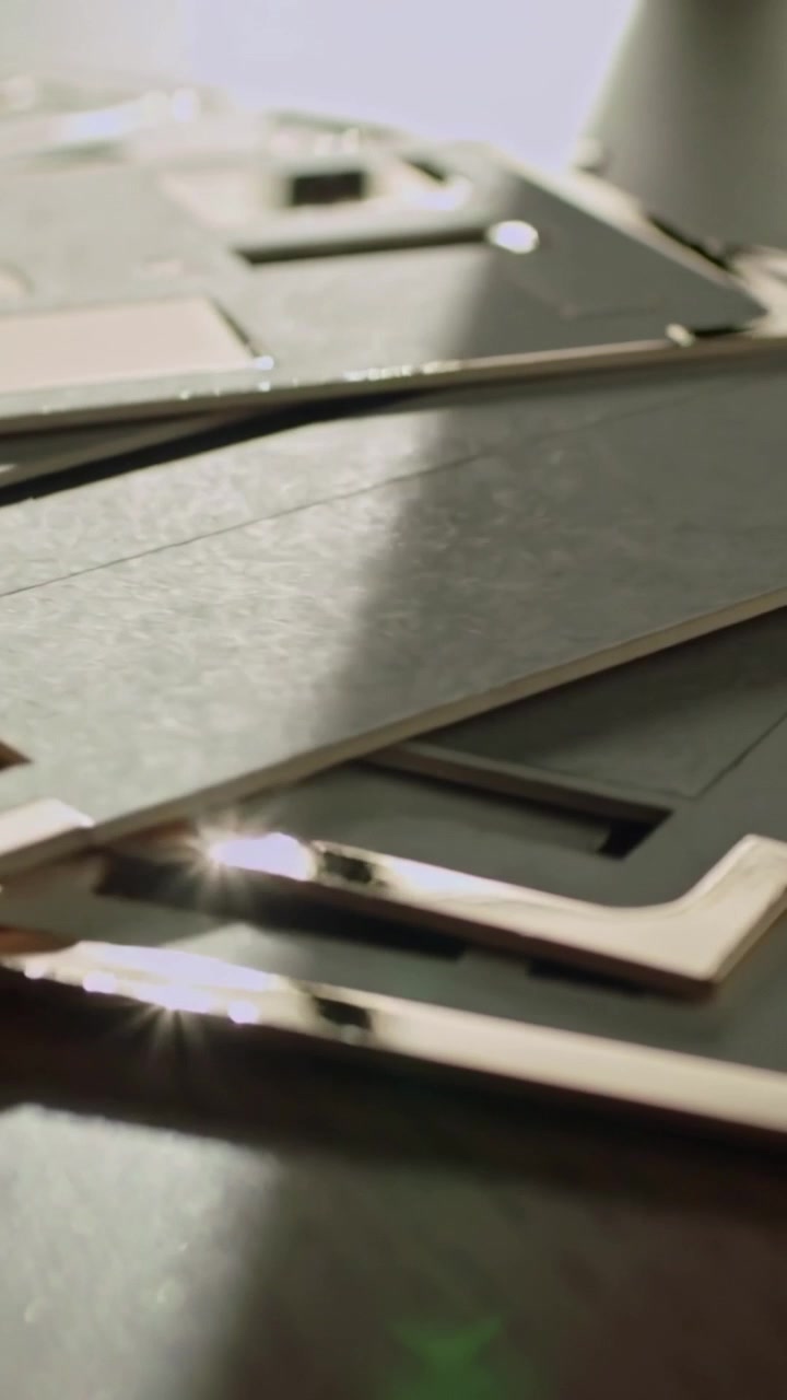 Vertikal video: Glidende kamera viser rosaguldkant over mørkt pap på et træbord, der viser glans.