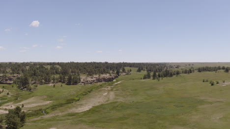 aerial views of a grassy plane heading to a beautiful rock formation in palmer lake colorado