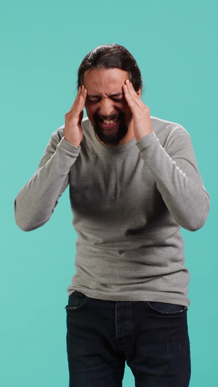 Vertical video Portrait of man feeling exhausted from overworking, suffering from headache