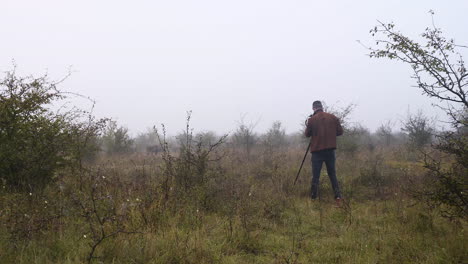 wildlife photographer shooting a lone bison bull in mist,from behind