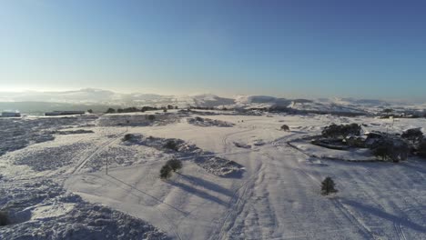 Cubierto-De-Nieve-Rural-Invierno-Campo-Pista-Huella-Sombras-Terreno-Vista-Aérea-Aumento-Pan-Derecha-Inclinación-Hacia-Abajo