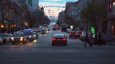 calle de la ciudad ocupada al anochecer con tráfico y peatones