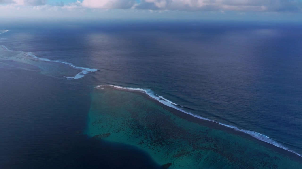 Pemandangan Samudra Pasifik Selatan dari udara, menampilkan terumbu karang dan ombak Teahupo'o yang pecah, diambil dengan drone di pulau Tahiti, Polinesia Prancis. Terlihat laguna cerah, aktivitas berselancar, pemandangan pelabuhan Passe Havea, lanskap dengan langit biru, dan pagi yang cerah.