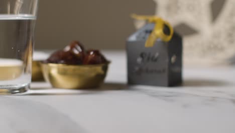 Bowl-Of-Dates-With-Sugar-And-Glass-Of-Water-Celebrating-Muslim-Festival-Of-Eid-With-Gift-Box-And-Symbol-Of-Pakistan