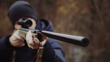 Man shooting gun in forest. Close up of male hunter in the forest aiming and shooting with hunting rifle