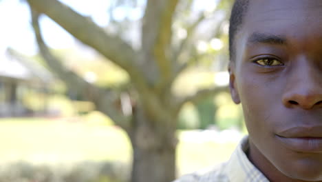 smiling african american man outdoors with tree in background, enjoying hot weather, copy space