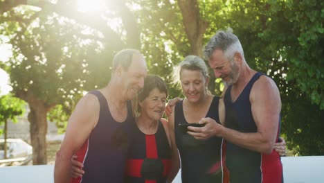 rowing team of four senior caucasian men and women using smartphone