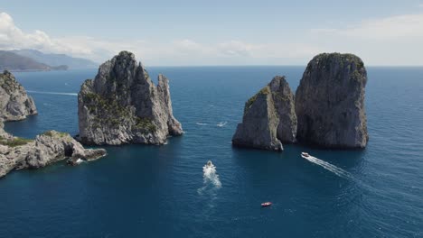 aerial view of boats cruising in the sea with faraglioni rock formation in capri, italy