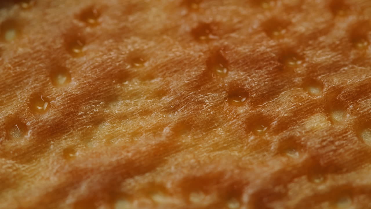 Macro Close-Up of Golden Cracker Surface Absorbing Oil