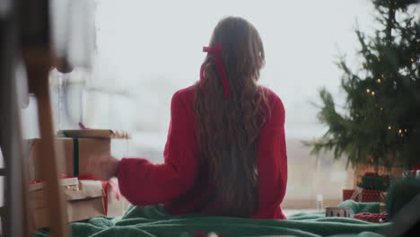 Woman-enjoying-coffee-while-looking-through-window-during-Christmas-at-home