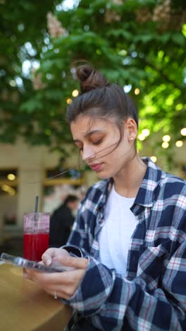 joven usando el teléfono en un café al aire libre