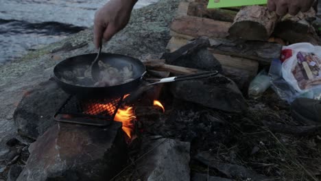 stirring meat and vegetables over an open flame.