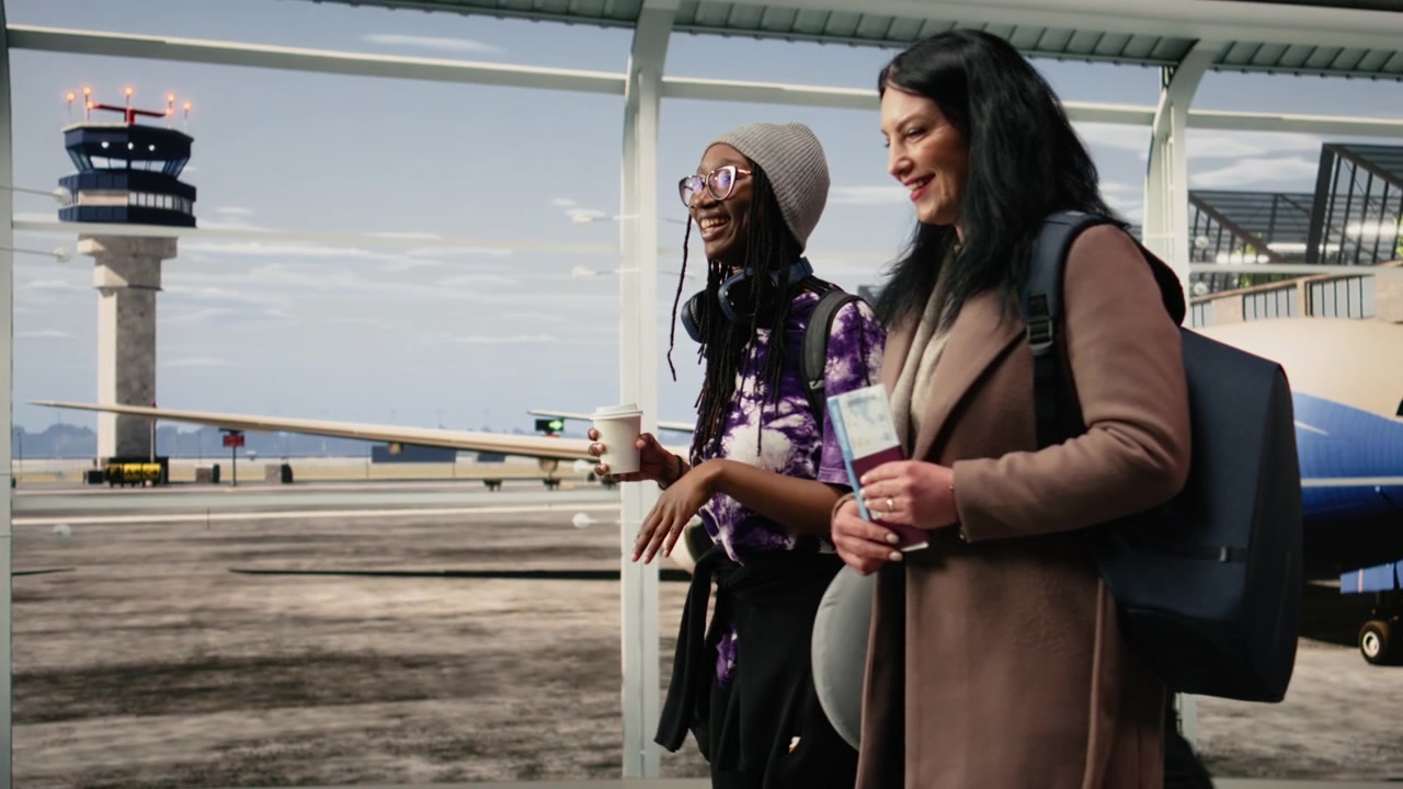 Female passengers carrying backpacks in airport terminal, travelling together