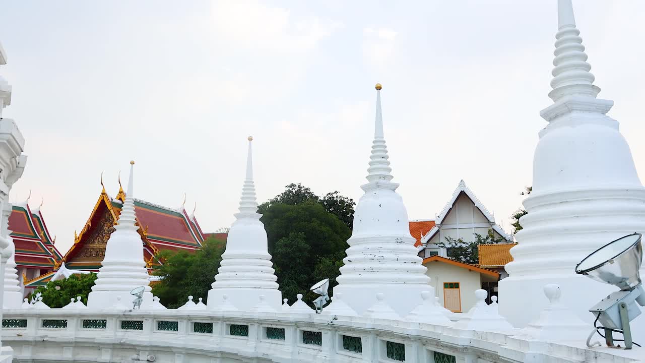 Un video tranquillo che mostra la splendida architettura di Wat Prayurawongsawat a Bangkok, con pagode bianche e vegetazione lussureggiante