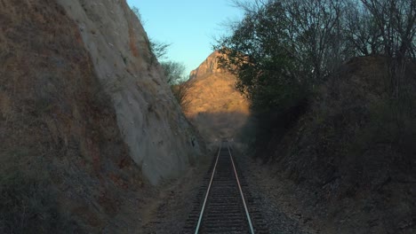 tilt up shot of a railroad and a big mountain at sunset from a moving train