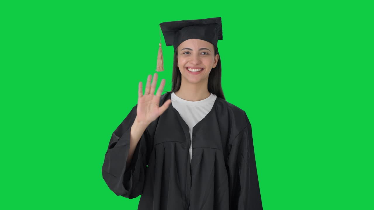 Ragazza indiana laureata felice che saluta la telecamera, schermo verde