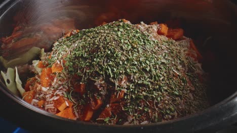 dried parsley and oregano dropped over heap of herbs in vegetable pot stew