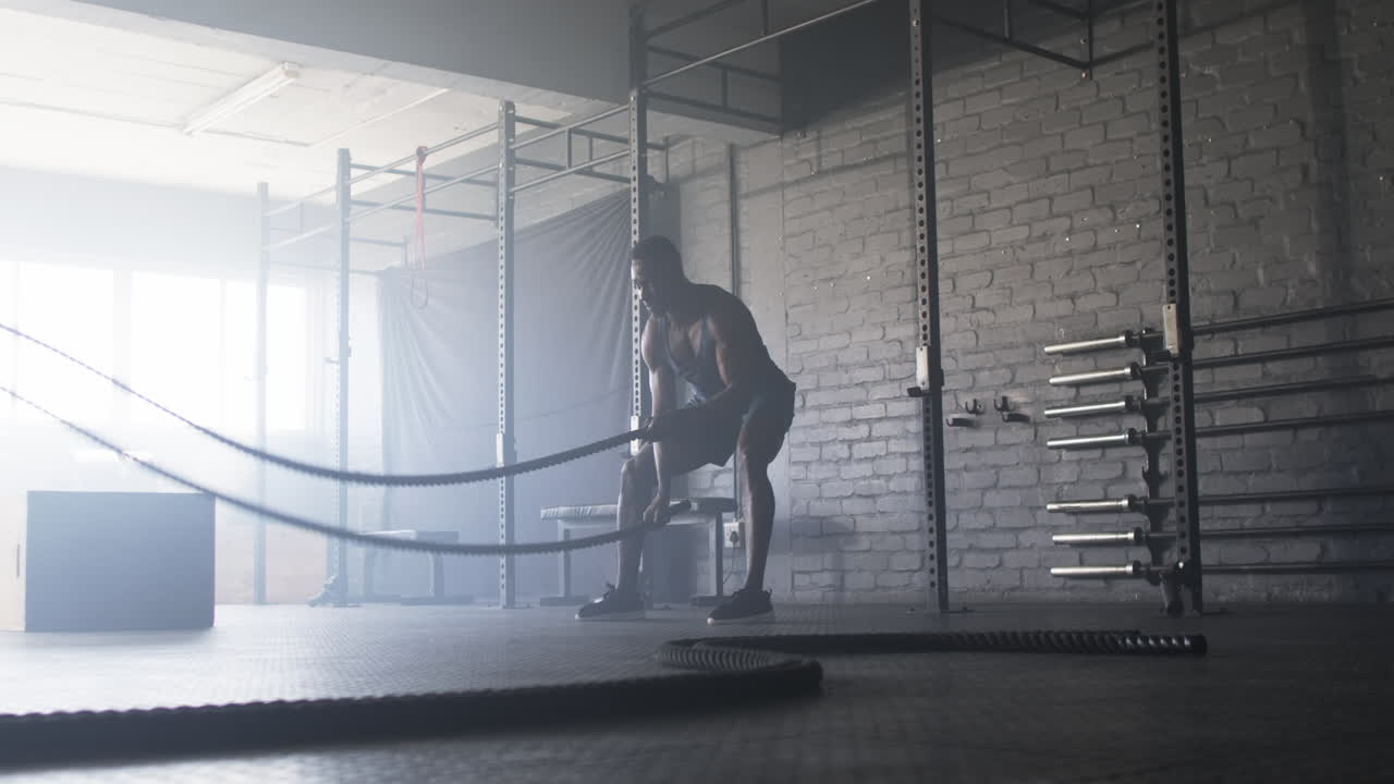 Uomo che si allena in palestra usando le battle ropes per un allenamento di forza.