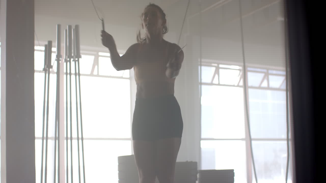 Jumping rope, strong fit woman exercising in gym, staying fit