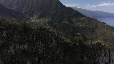 A-dron-clip-circling-around-a-young-man-standing-on-the-edge-of-a-cliff-in-Madeira