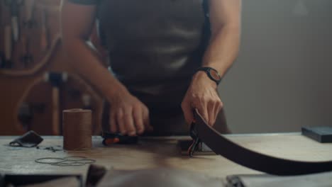 artisan hands crafting a leather belt in a workshop