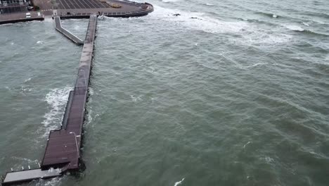 antena de drones sobre el muelle del océano en melbourne día nublado ventoso ondulado