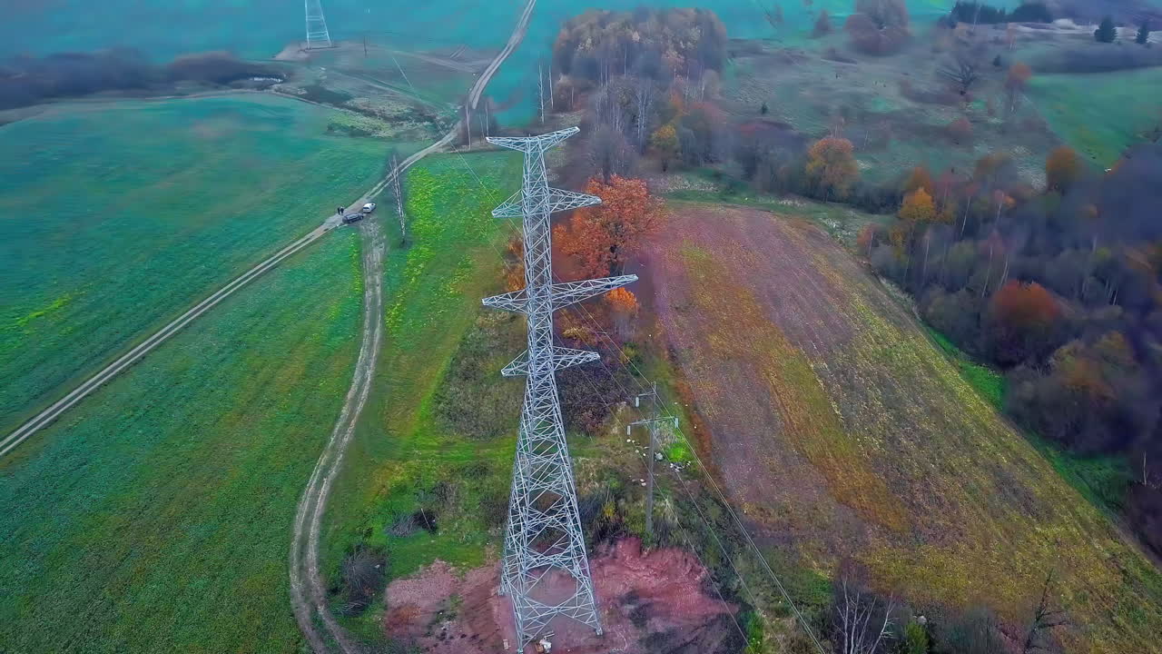 고전압 전기 타워 주변을 돌고 있는 드론은 나중에 광활한 녹색 풍경을 보여줍니다.