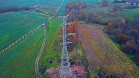 Drone-circling-around-high-voltage-electricity-tower-later-reveals-the-vast-green-landscape