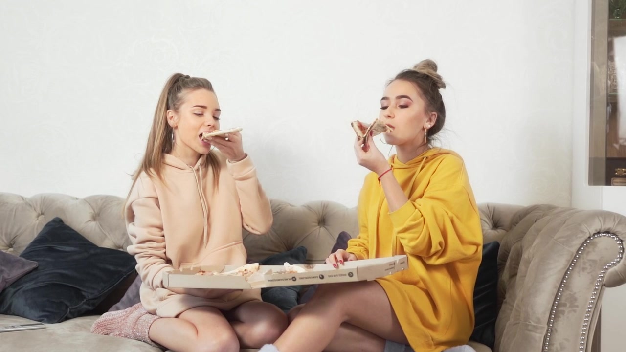 Ragazza che mangia pizza a domicilio seduta sul divano