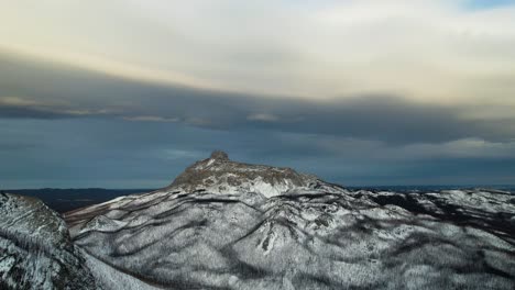 Drone-Gimbal-Abajo-Revelando-La-Pendiente-Nevada-De-Una-Montaña-Gigante-En-Las-Montañas-Rocosas,-Alberta