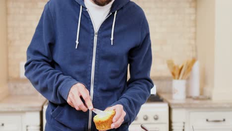 Young-man-applying-butter-on-cupcake-and-having-it-4K-4k