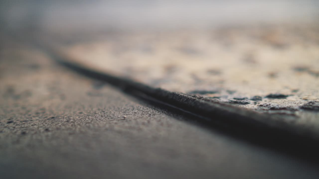 Close-up of sea water flowing up and down over a rope on the shoreline making bubbles during golden hour - Blurry background