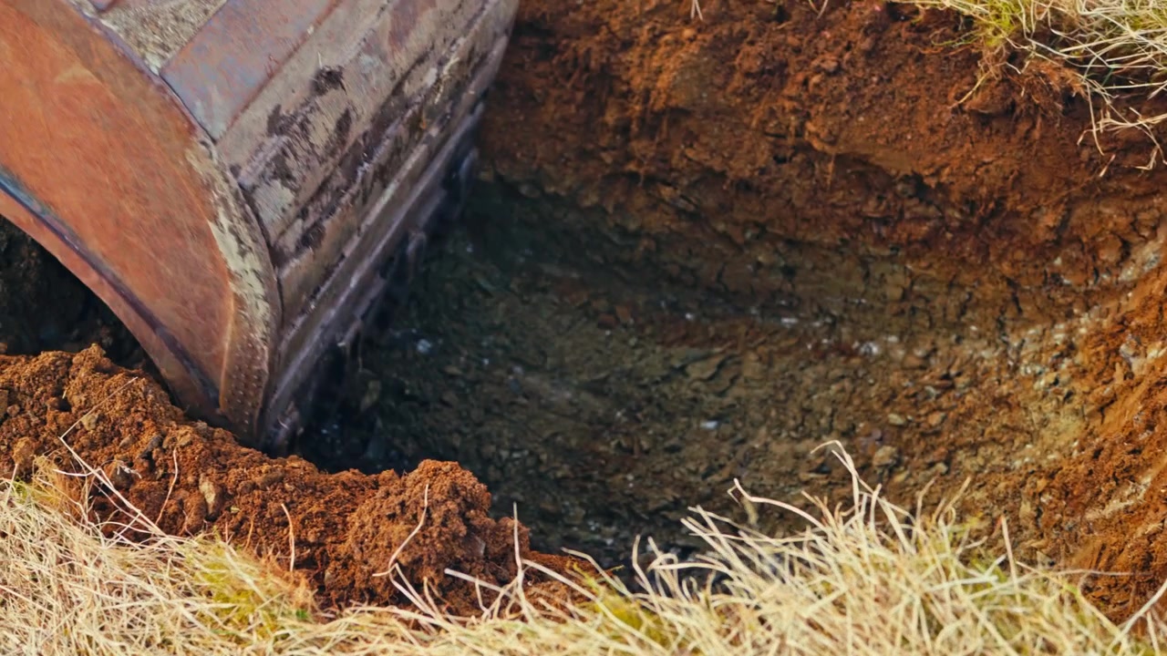 An excavator bucket digs into soil on a farm in Norway - close up