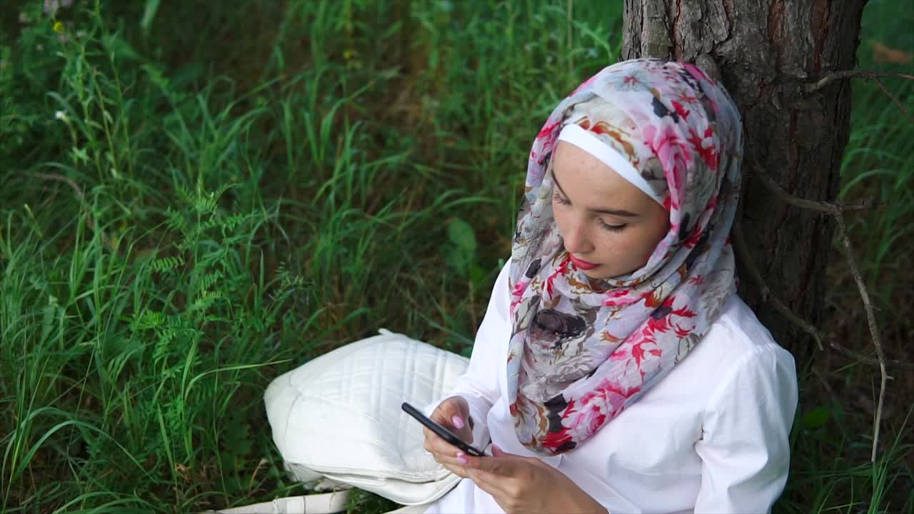 Young Woman in Hijab Using Smartphone Outdoors