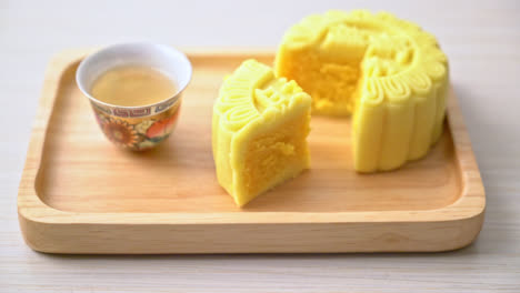 Chinese-moon-cake-custard-flavour-with-tea-on-wood-plate