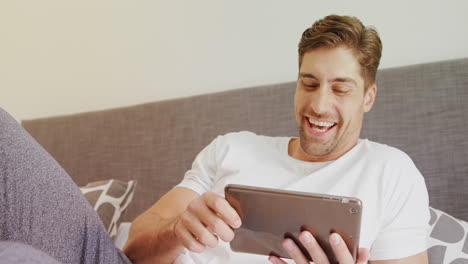 hombre sonriente usando tableta digital en la cama 4k 4k