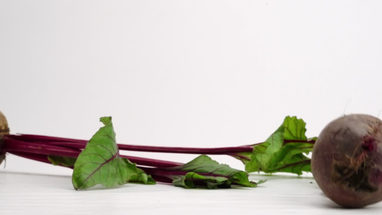 전체 사탕무 뿌리가 4k 느린 동작으로 흰색 스튜디오 배경에서 떨어지고 튀는