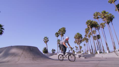 vista en ángulo bajo de un ciclista bmx ejecutando un salto y girando en un skatepark