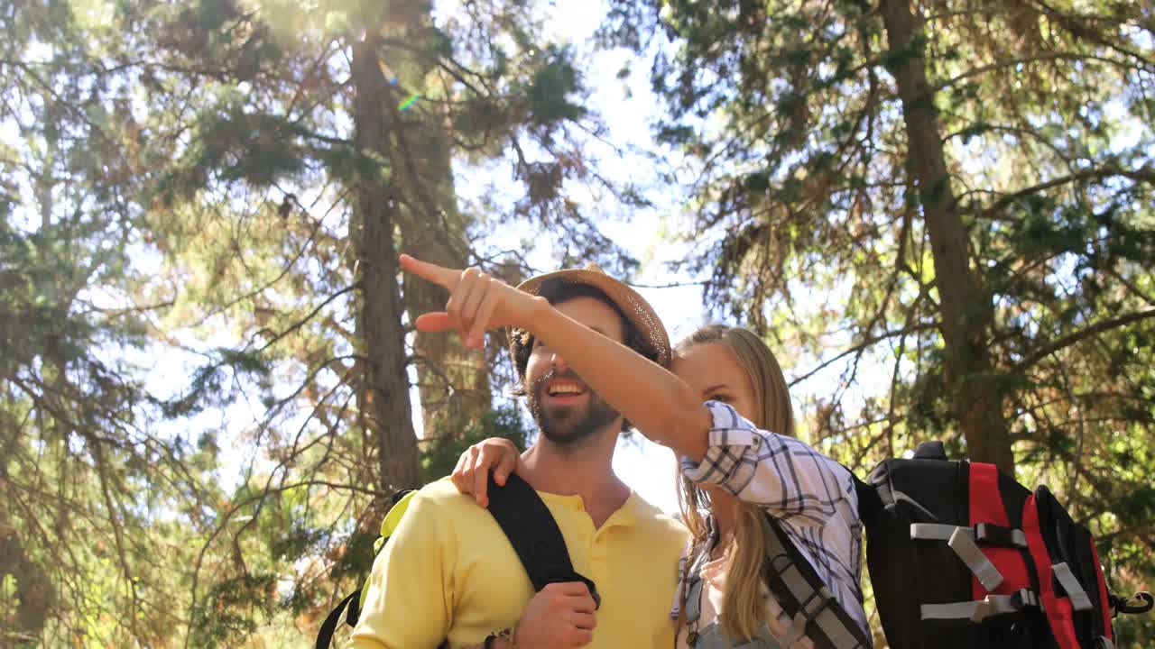 una pareja de excursionistas de pie y señalando lejos en el bosque