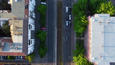 Die-Kamera-Verfolgt-Den-Autoverkehr,-Wartet-An-Einer-Kreuzung-Und-Fährt-Sanft-Los.-Luftaufnahme,-Flugdrohne,-Draufsicht-Auf-Berlin,-Prenzlauer-Berg-Allee,-Sommer-2022