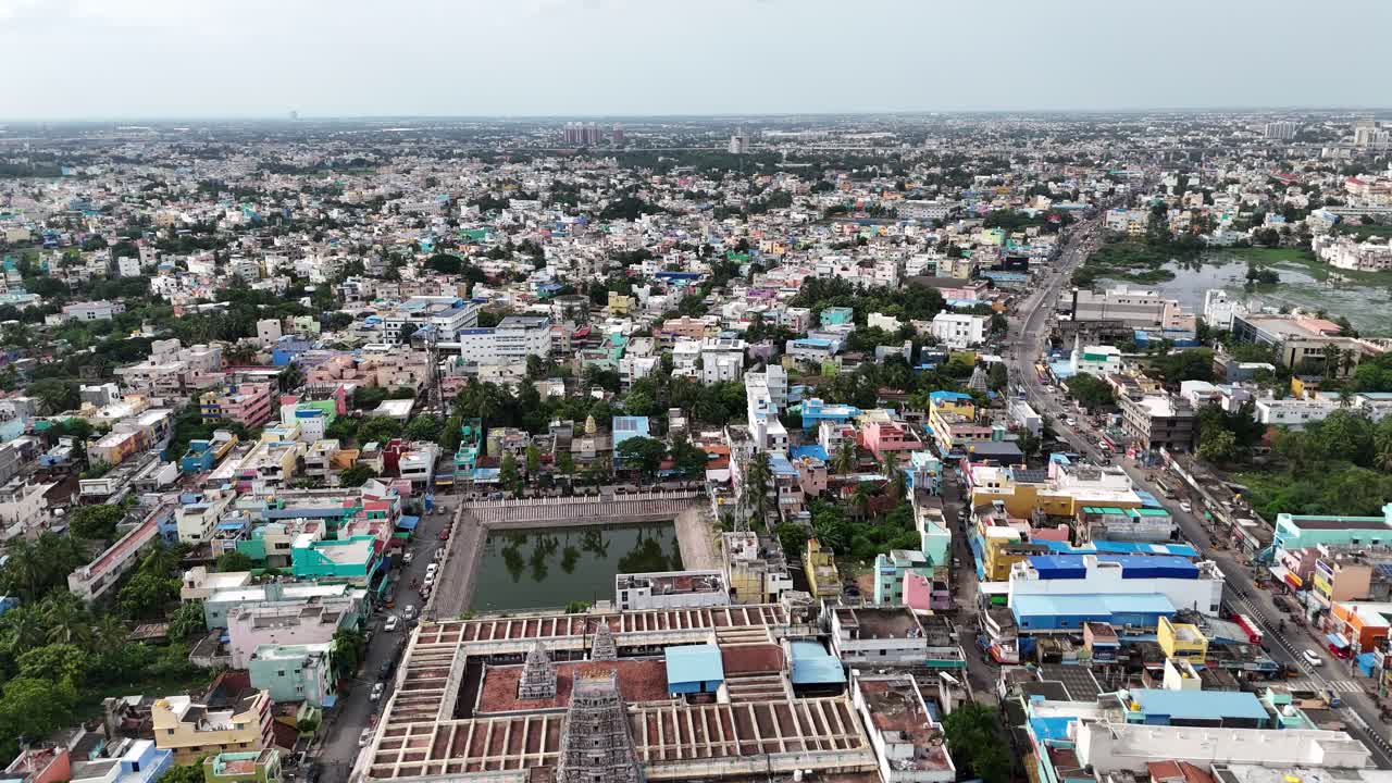 Aerial shot of a vast, dense Indian cityscape centered on a traditional Sri Kamakshi Amman Temple Mangadu complex and its square Theppakulam (water tank). Heritage meets urban sprawl