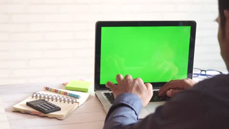 person working on laptop with green screen