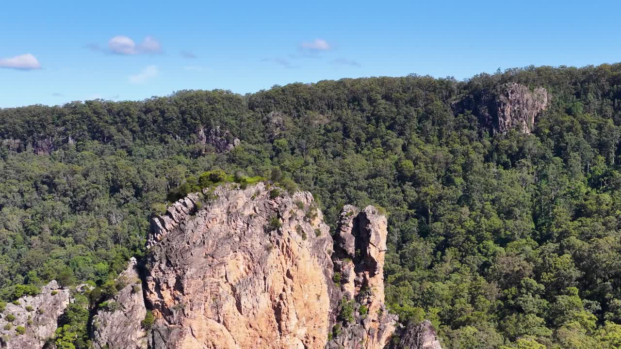 Aerial footage of Nimbin Rocks, showcasing dramatic rock formations and lush forests under clear skies
