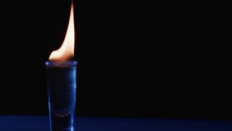 Video-of-lit-alcohol-in-glass-with-yellow-fire-flames-and-copy-space-on-black-background