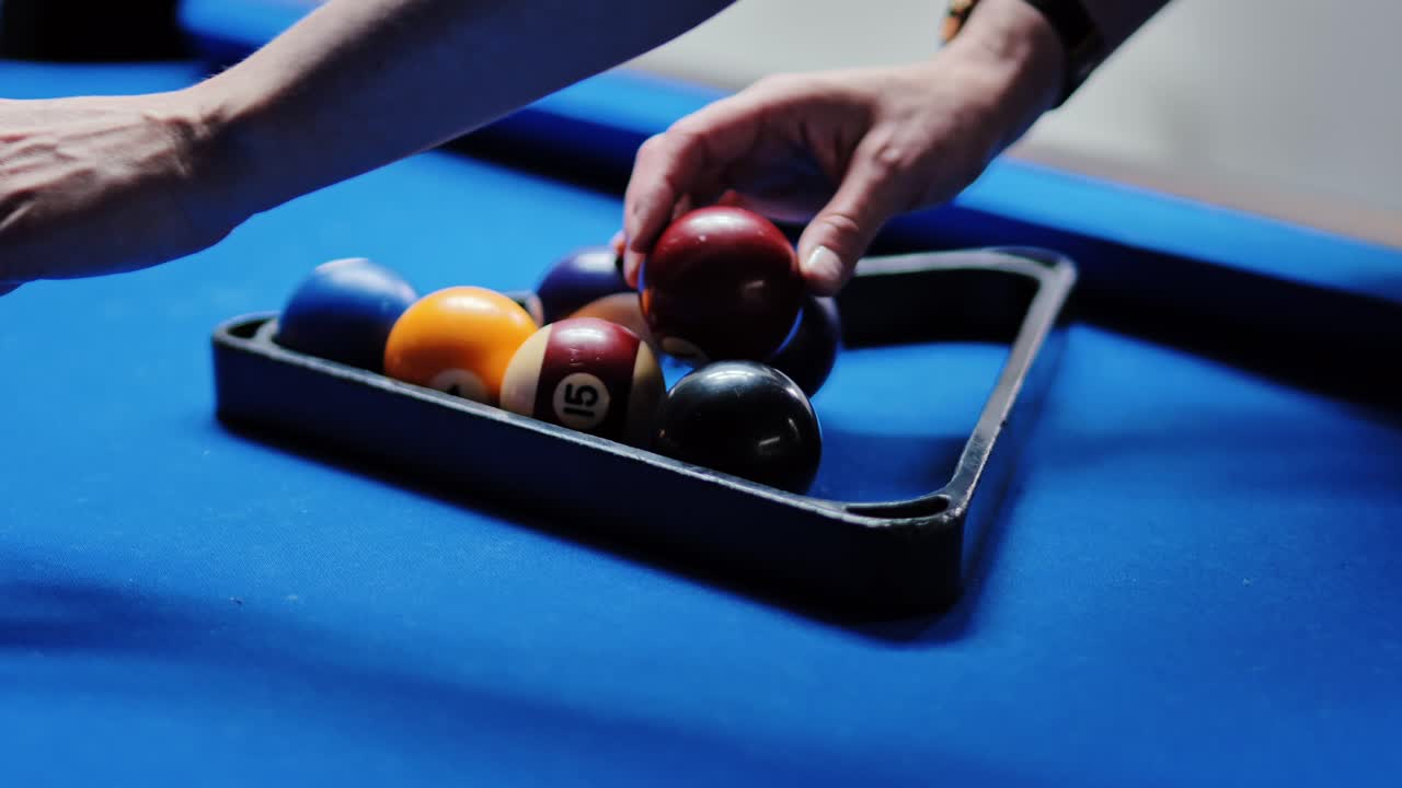Une main élégante avec une bague arrange délicatement des boules de billard colorées avant le match