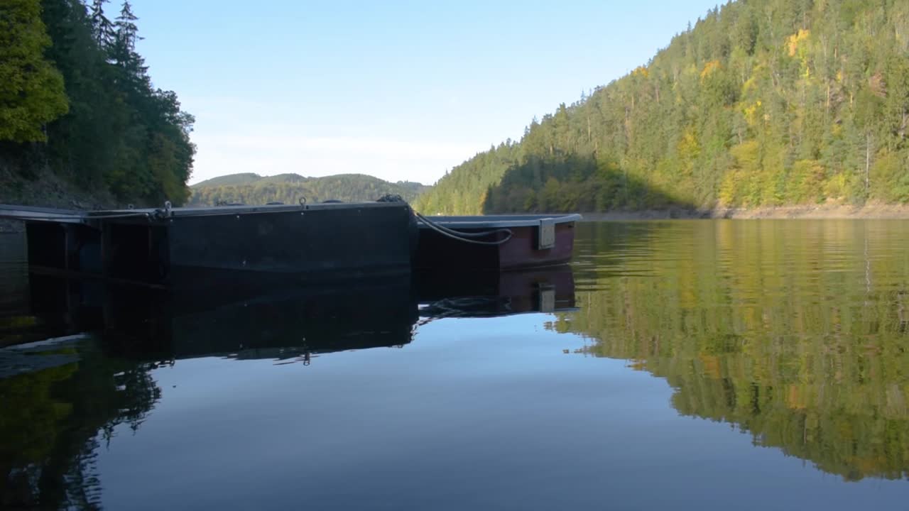 배경에 산이 있고 전경에 나무 상륙 무대가 있는 큰 호수의 목가적인 탁 트인 전망