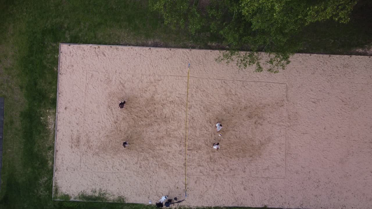 grupo de mujeres jugando voleibol en la superficie arenosa, vista aérea de arriba hacia abajo