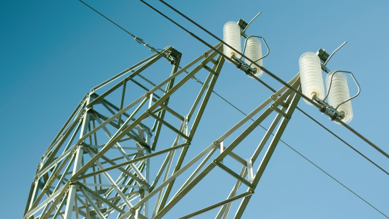 primer plano de aisladores en pilón eléctrico, fondo de cielo azul